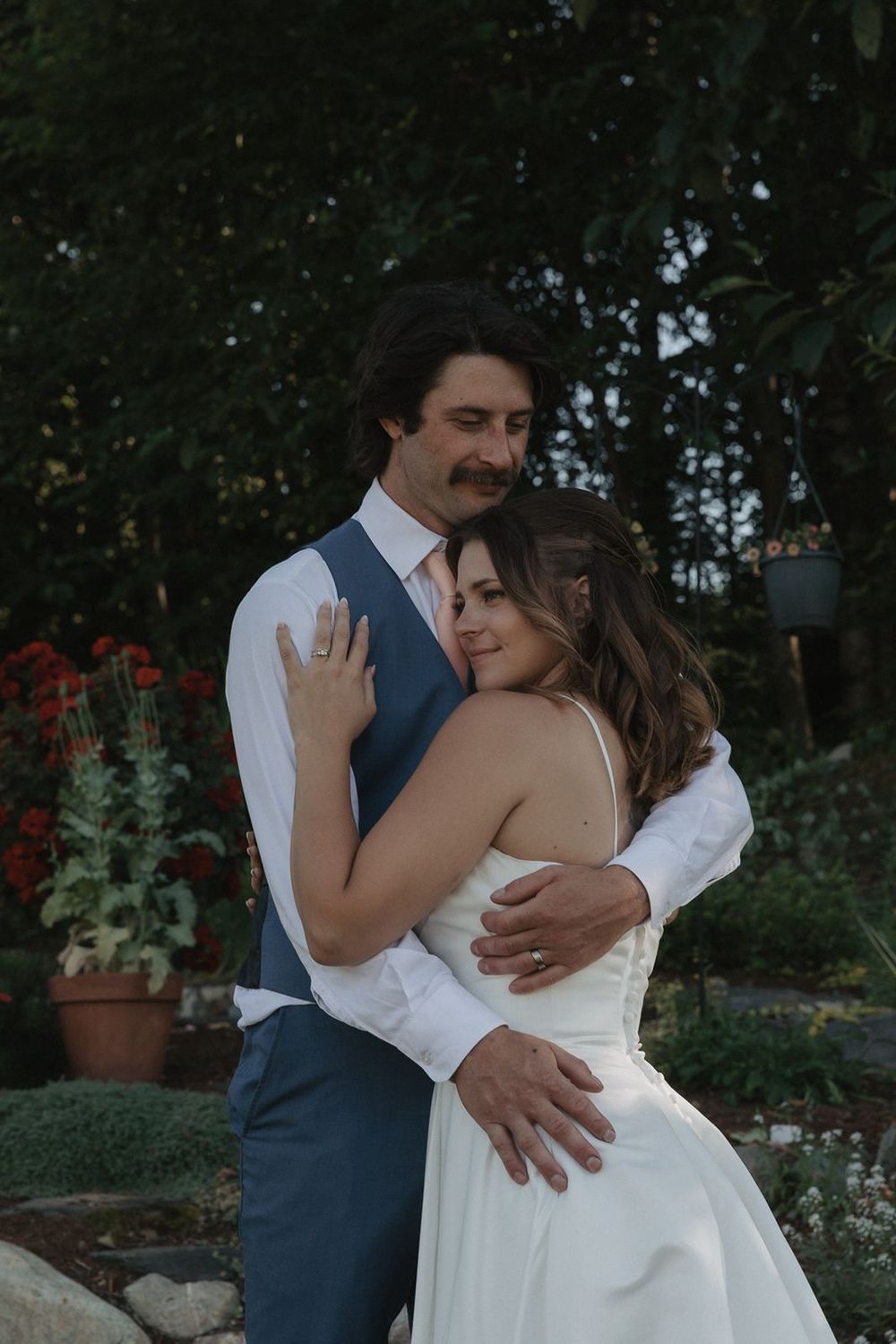 Bride and groom sharing a tender embrace in a lush garden setting at their outdoor wedding.