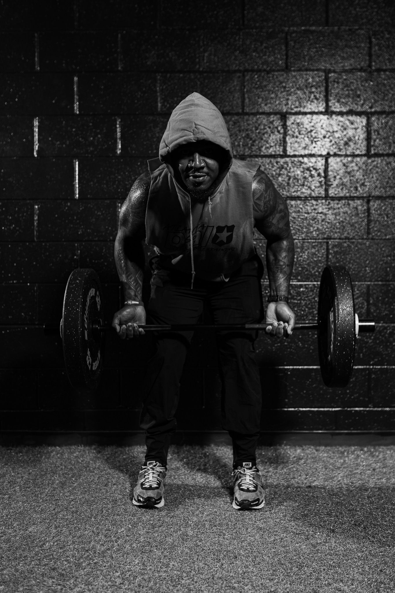 A sequence of black and white photos showing someone performing a dumbbell exercise against a dark wall.