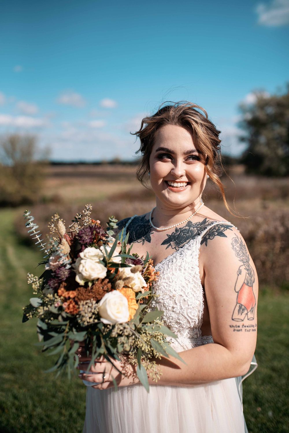 Portrait of bride outdoors holding floral bouquet.