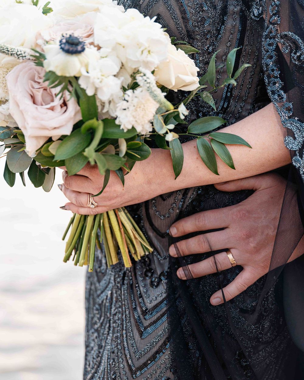 Detail picture of bride's floral bouquet with groom's hands.