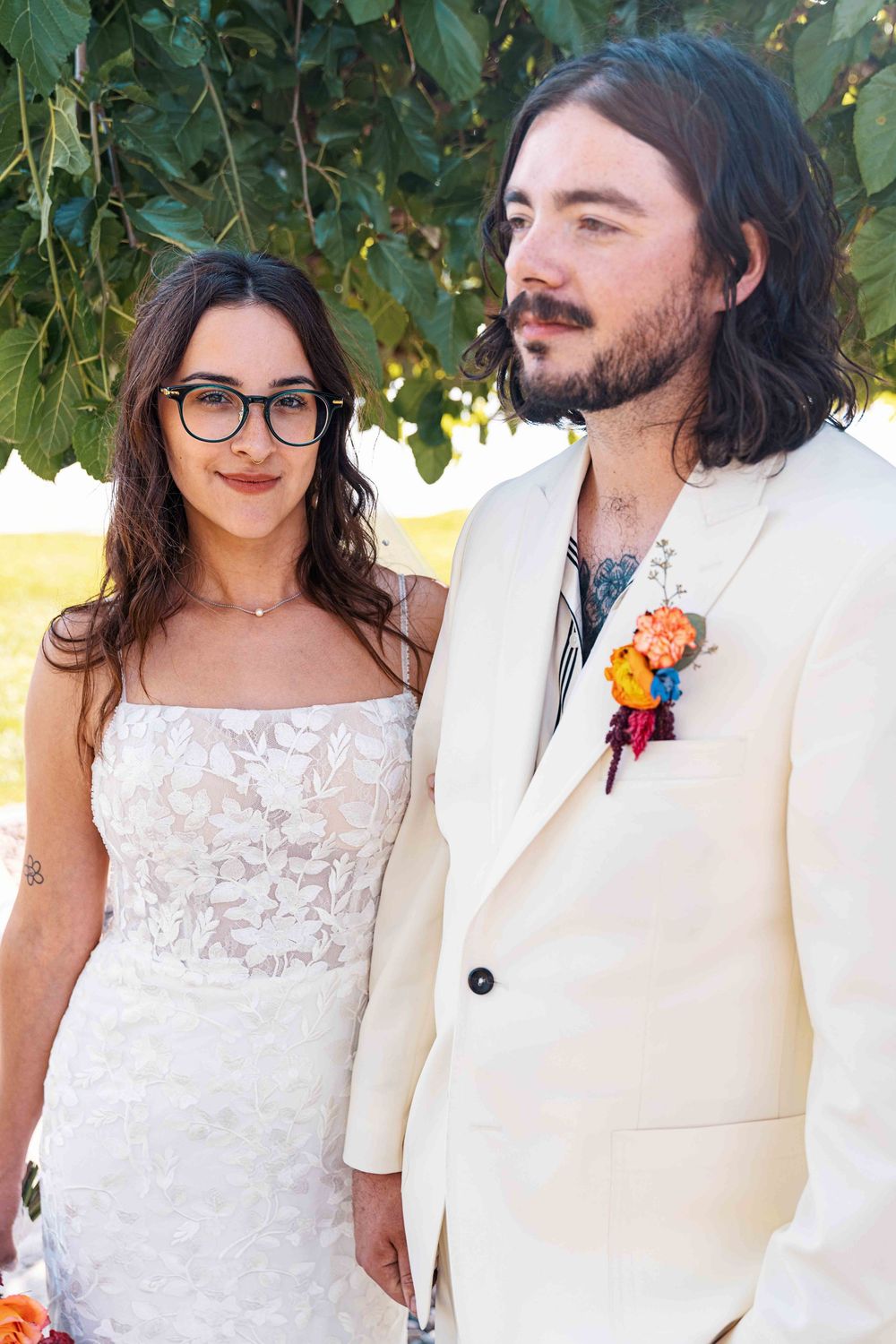 Portrait of bride and groom wearing white photographed outdoors.
