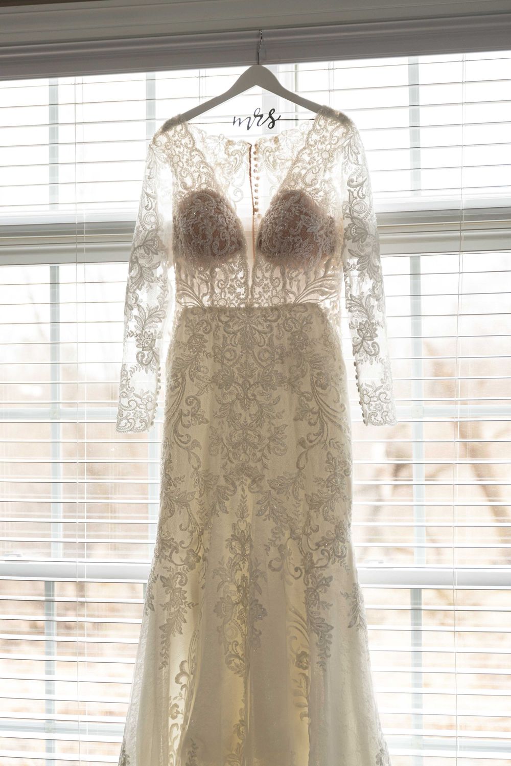 Detail picture of wedding dress hung in window.