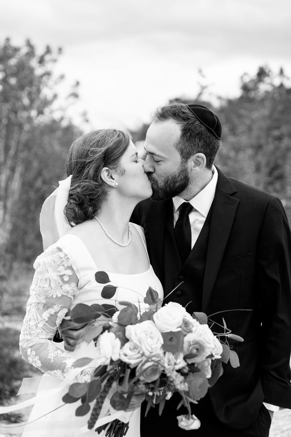 Black and white portrait of bride and groom kissing.