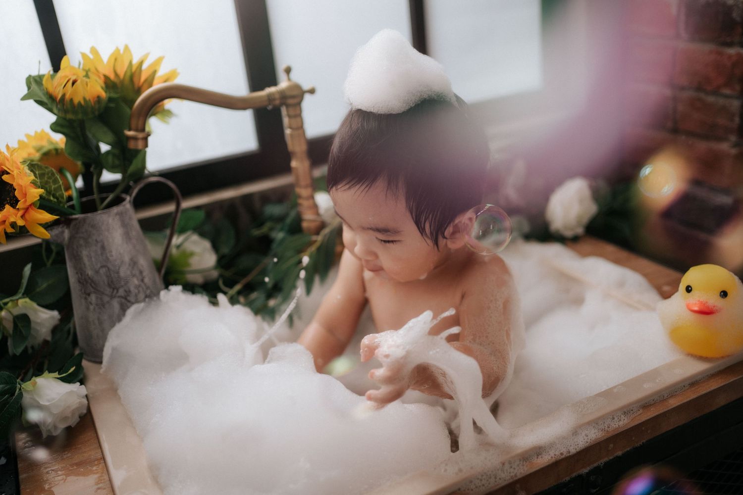 A series of cake smash photos showing a baby in white outfit with blue cake and floral decorations in a bright studio setting.