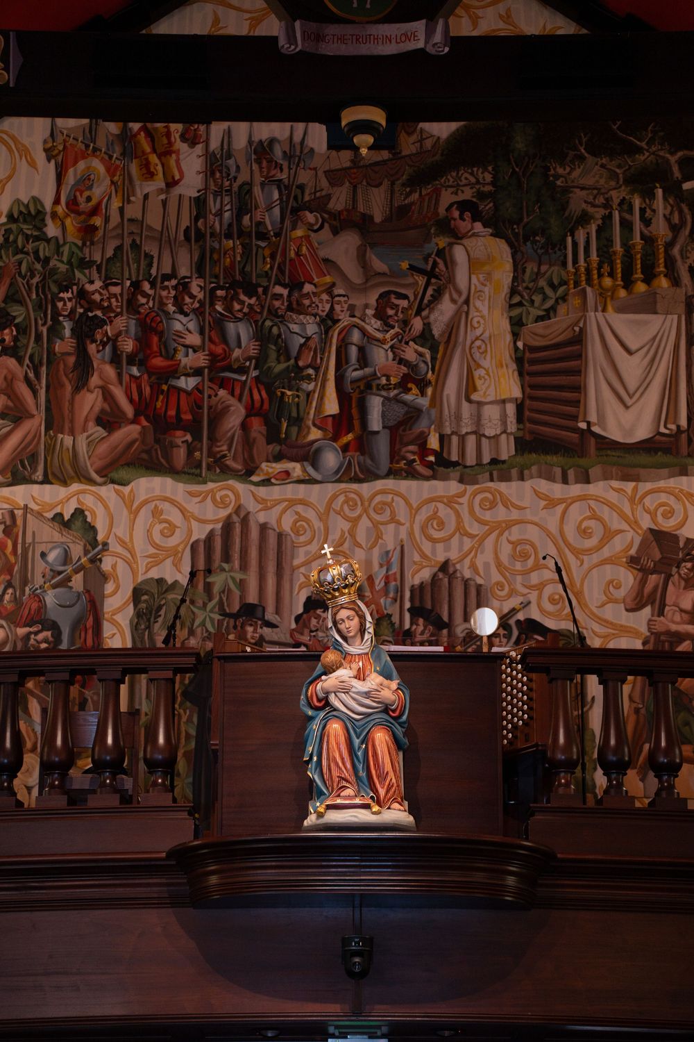 Artistic murals and decorative paintings adorn the walls of a dimly lit interior space with dramatic lighting.