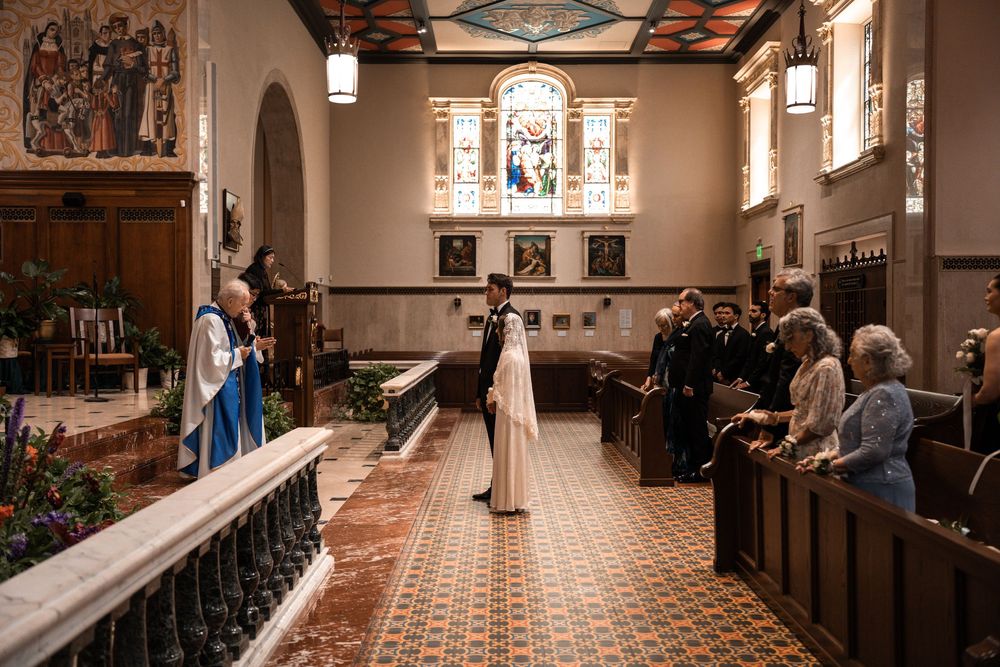 Church interior panorama showing ornate ceiling, wooden pews, and stained glass windows in warm lighting.