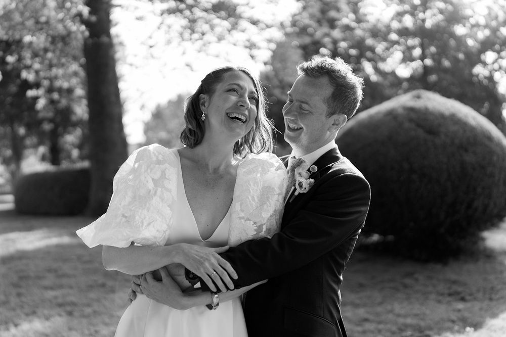 A black and white photo series captures intimate moments between a bride and groom in an outdoor garden setting.