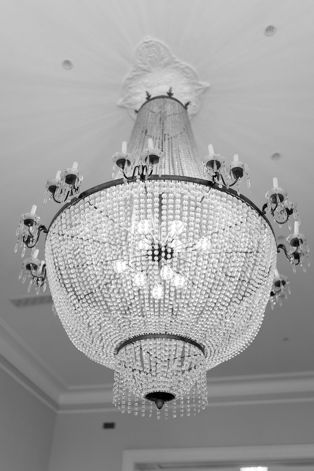 Crystal chandelier with cascading beads and black metal arms photographed from multiple angles in a white room.
