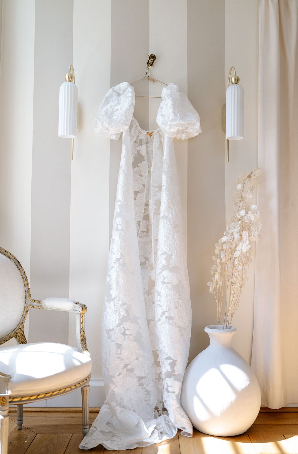 A series of illuminated white paper lantern floor lamps with lace-like patterns create an ethereal glow in a room.