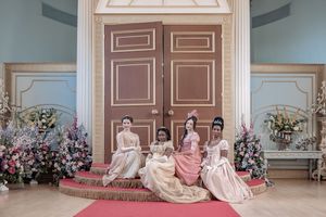 Behind the scenes of a Bridgerton Netflix filming setup at Newark Town Hall, showing four ballroom ladies posed on red carpet steps.