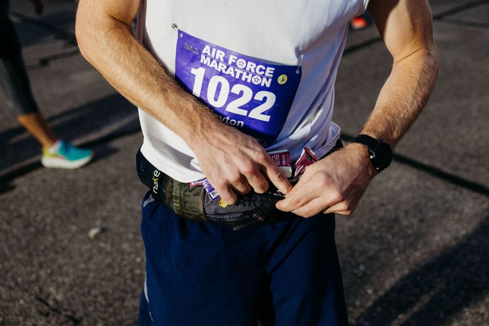 Runner attaches race bib number 1022 to their belt before a competition.