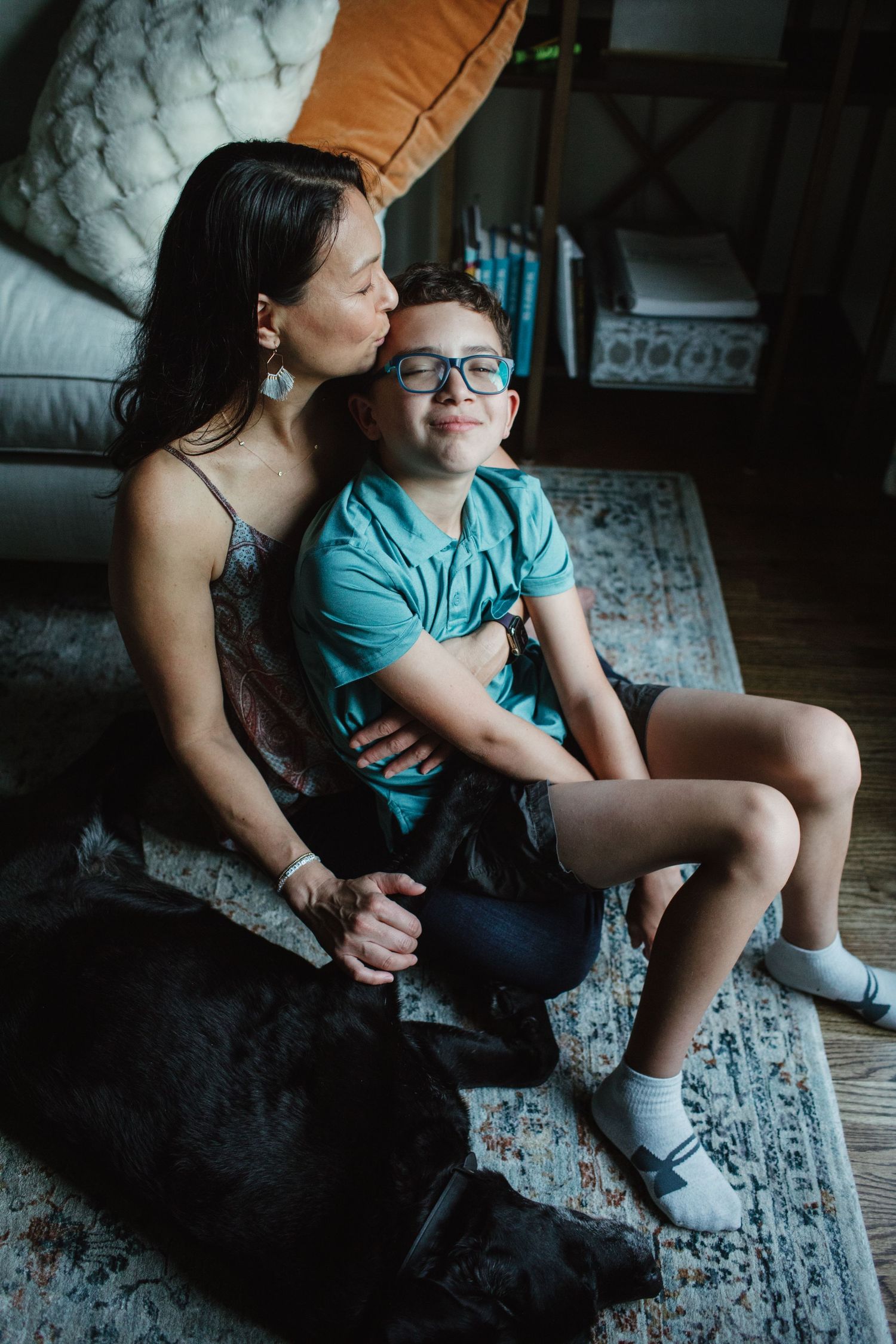 Intimate family moment captured on a patterned rug showing tender connection between parent and child.