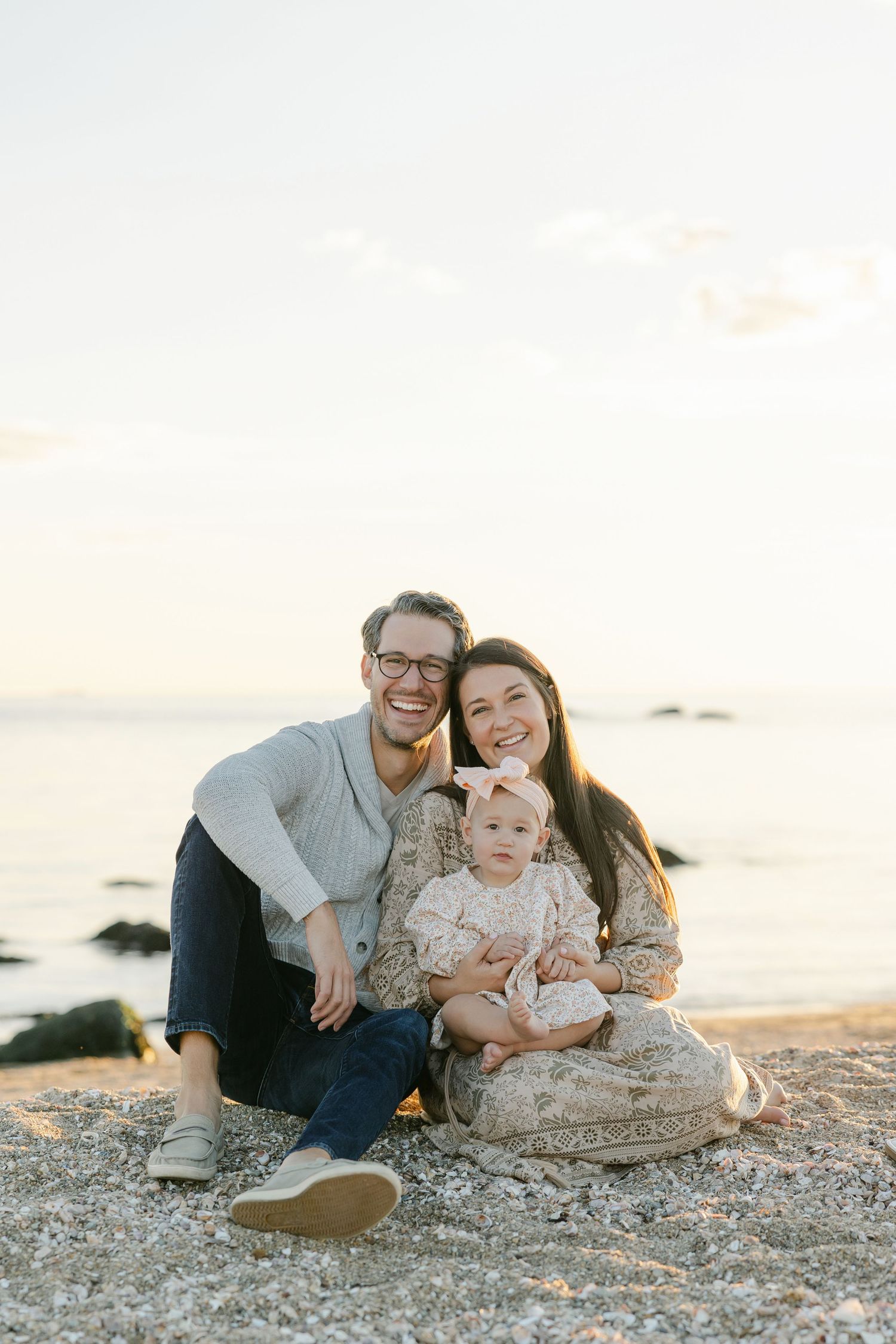 A family relaxes together on a rocky beach at sunset creating a warm and intimate moment by the ocean.