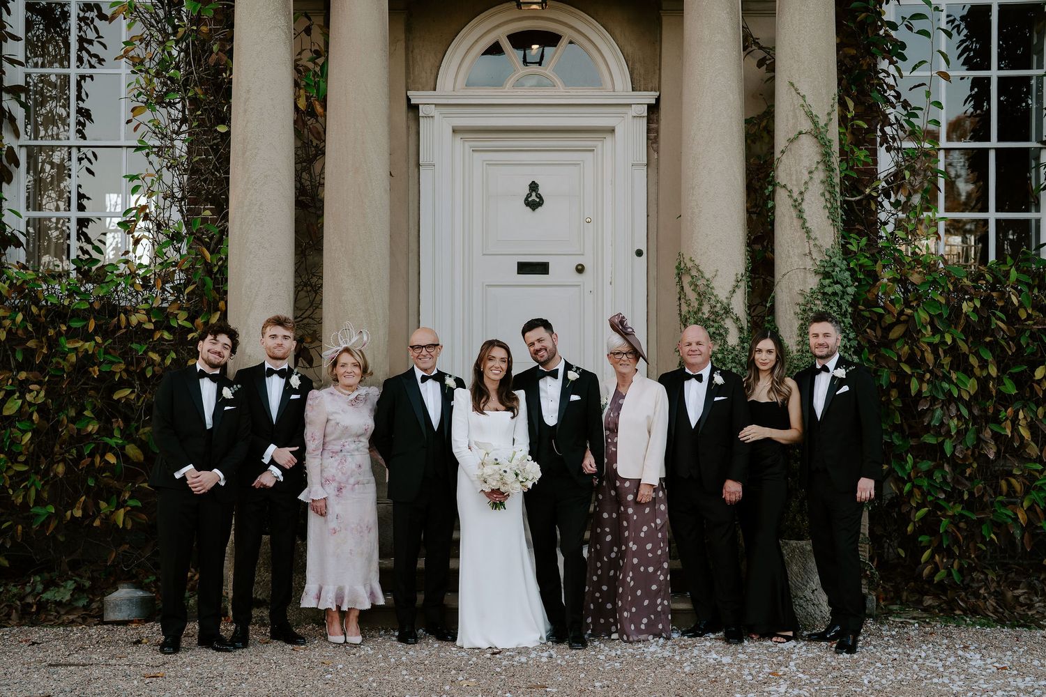 bride and groom and families smiling for a portrait outside Iscoyd park
