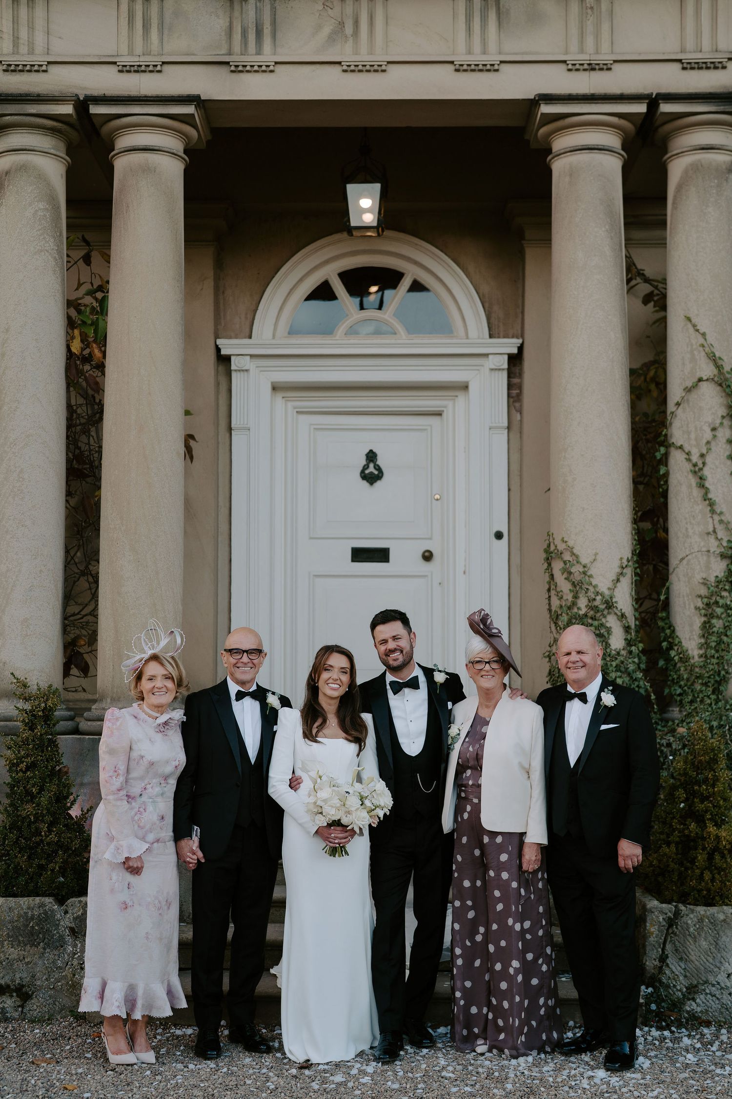 bride and groom and parents smiling for a portrait outside Iscoyd park