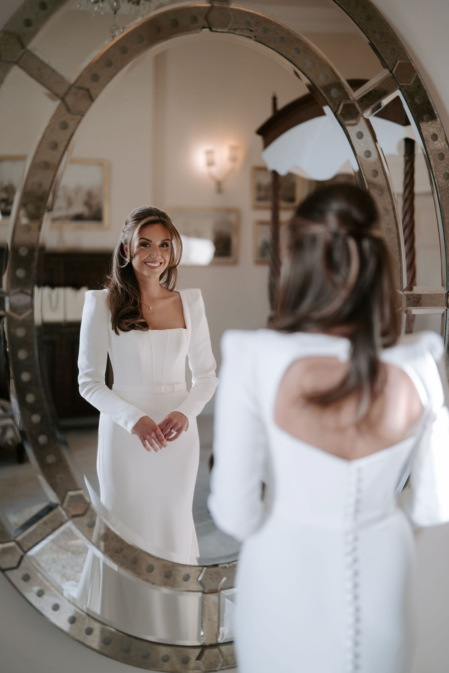 bride looking back at herself in the mirror smiling before her ceremony at Iscoyd park