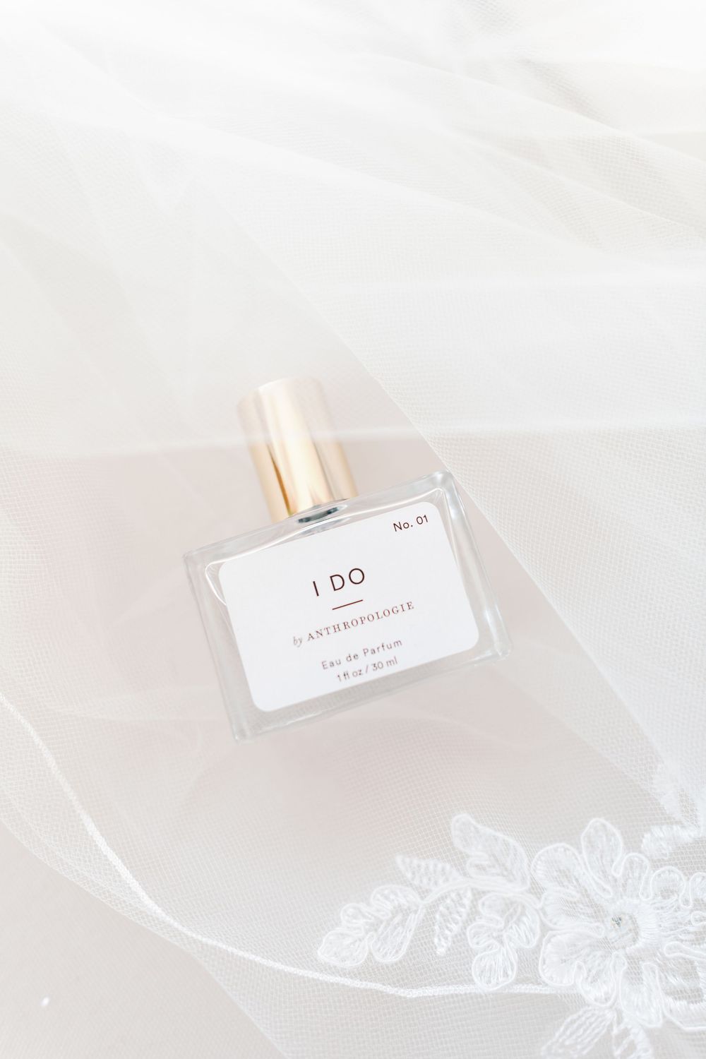 Anthropologie I DO eau de parfum bottle resting on delicate lace bridal veil for wedding detail photo.