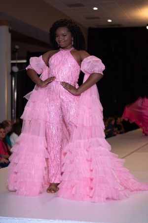 Models showcase voluminous pink tulle gowns with ruffled tiers on a fashion runway.