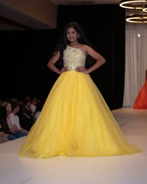 Stunning yellow ball gown with sequined bodice showcased on illuminated catwalk.