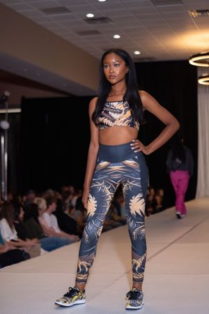 Models showcase patterned athletic wear on a fashion runway with dramatic lighting and audience seating.