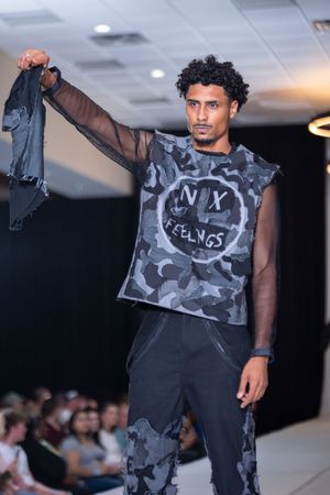 Models present urban streetwear featuring camouflage prints and graphic designs on the catwalk.