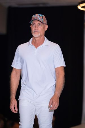 All-white casual ensemble with polo shirt and pants presented during fashion show.