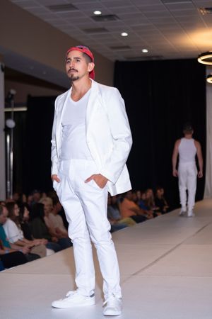 Crisp white suit with matching sneakers showcased on fashion runway.