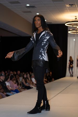 Avant-garde menswear featuring metallic silver and black jacket with slim pants on catwalk.