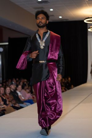 Modern fusion menswear with black and purple silk tunic and embellished neckline on runway.