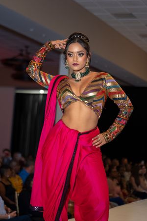 Contemporary fusion wear featuring striped crop top and flowing red draped pants on runway.