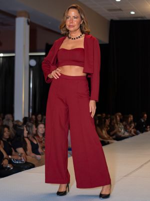 A burgundy crop top and wide-leg pants ensemble with matching cardigan on display at a fashion show.
