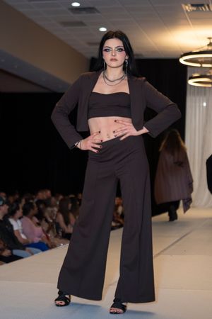 A sleek black crop top and wide-leg pants combination with blazer shown on a fashion runway.