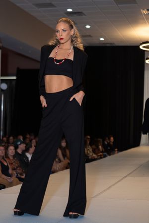 Model presents sleek black ensemble with wide-leg pants on fashion runway.
