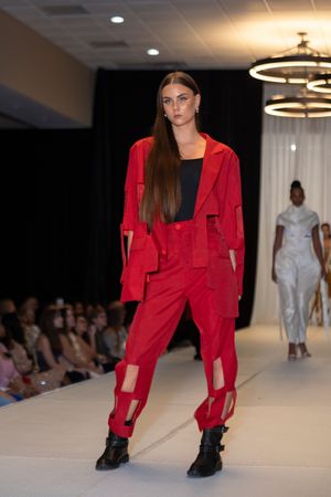 Model showcases bold red streetwear ensemble with black boots on catwalk.