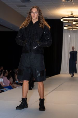Dark monochromatic outfit with shorts and sparkly jacket styled with combat boots on catwalk.