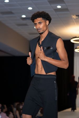 Athletic black ensemble demonstrated on fashion runway with dramatic lighting.