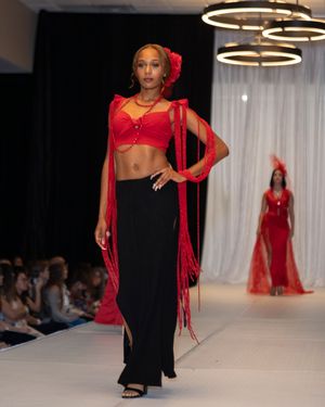 Dramatic red crop top with flowing sheer sleeves paired with black maxi skirt on runway.