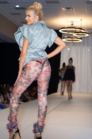 Model displays light blue top with patterned pink pants on catwalk.