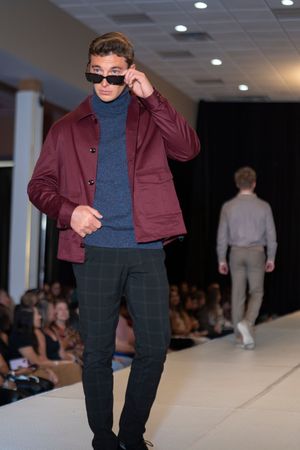 Burgundy jacket paired with navy turtleneck and dark pants shown on runway.