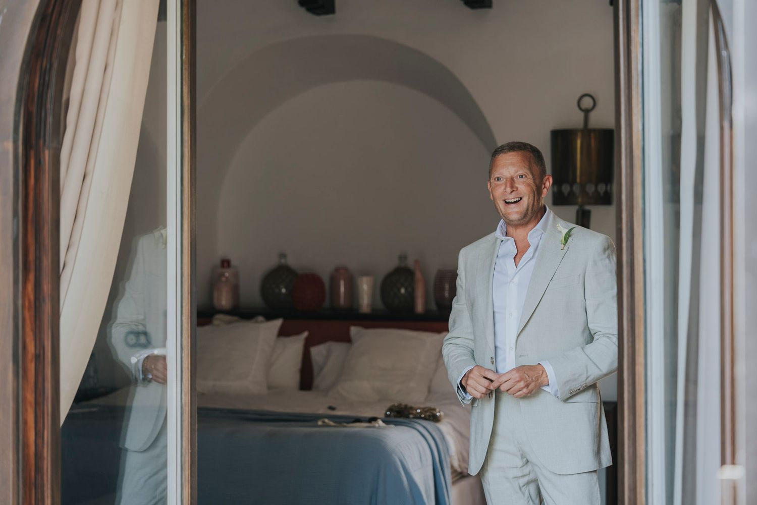 A couple in formal white attire sharing a joyful moment together in an elegant indoor setting.