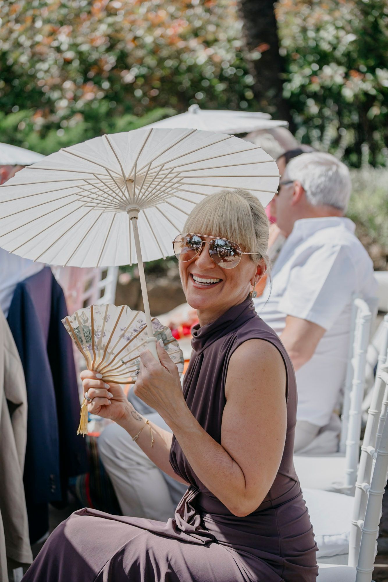 Guest enjoying the outdoor wedding celebration under a decorative white parasol.