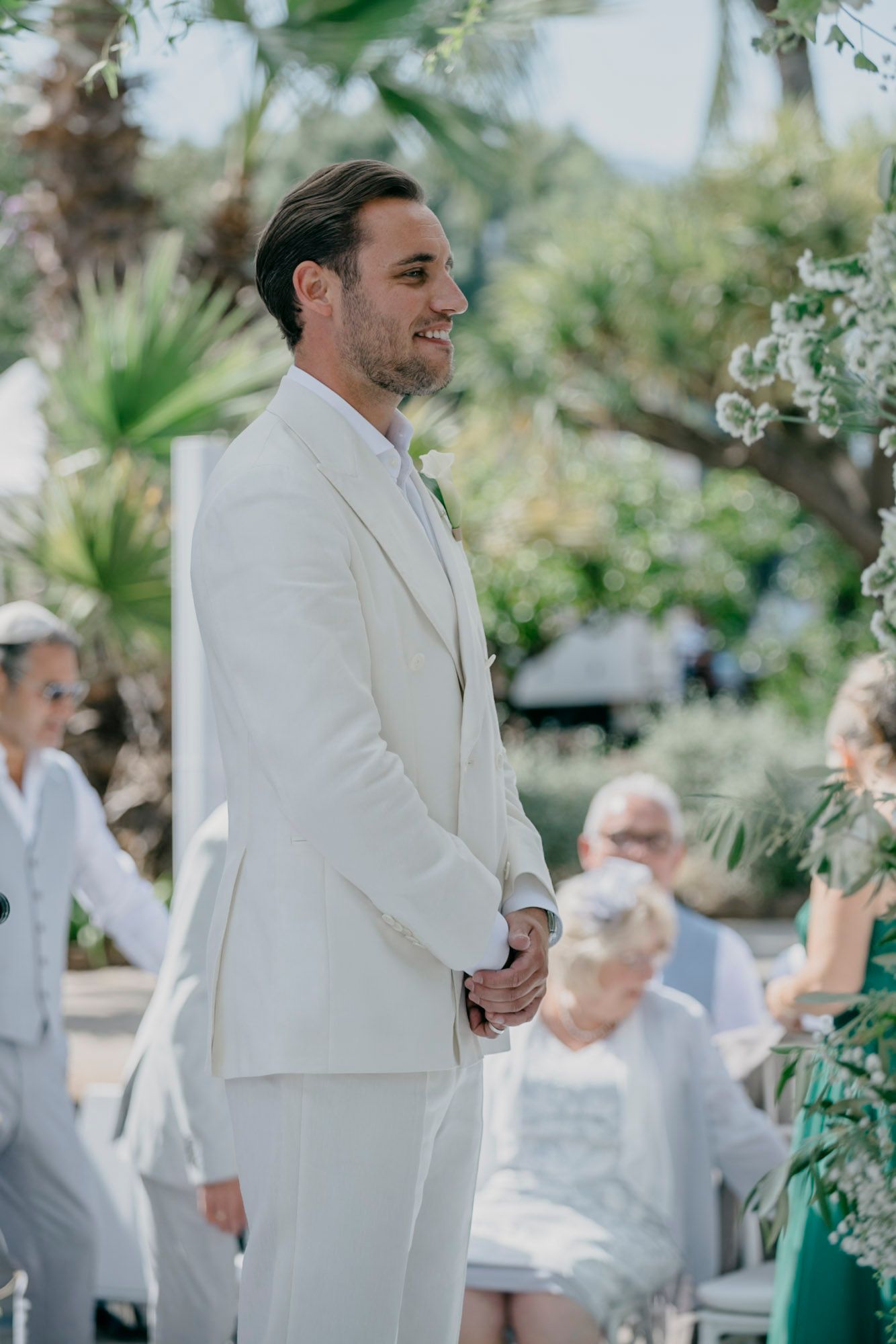 Outdoor wedding ceremony in a lush garden setting with white decor and tropical plants.
