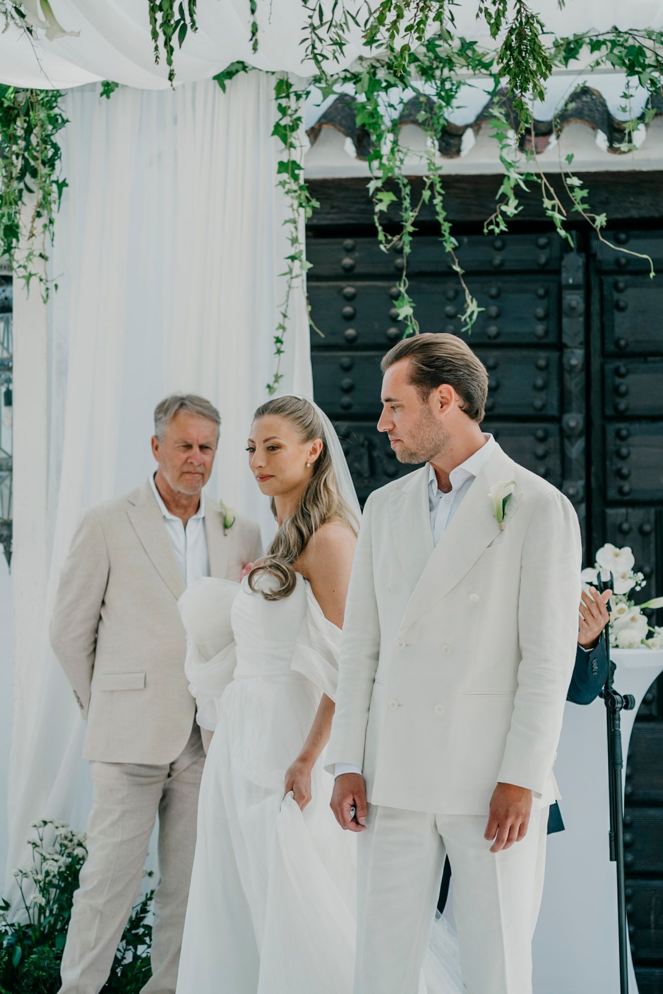 Wedding ceremony setup with white draping and hanging greenery creating an elegant outdoor atmosphere.