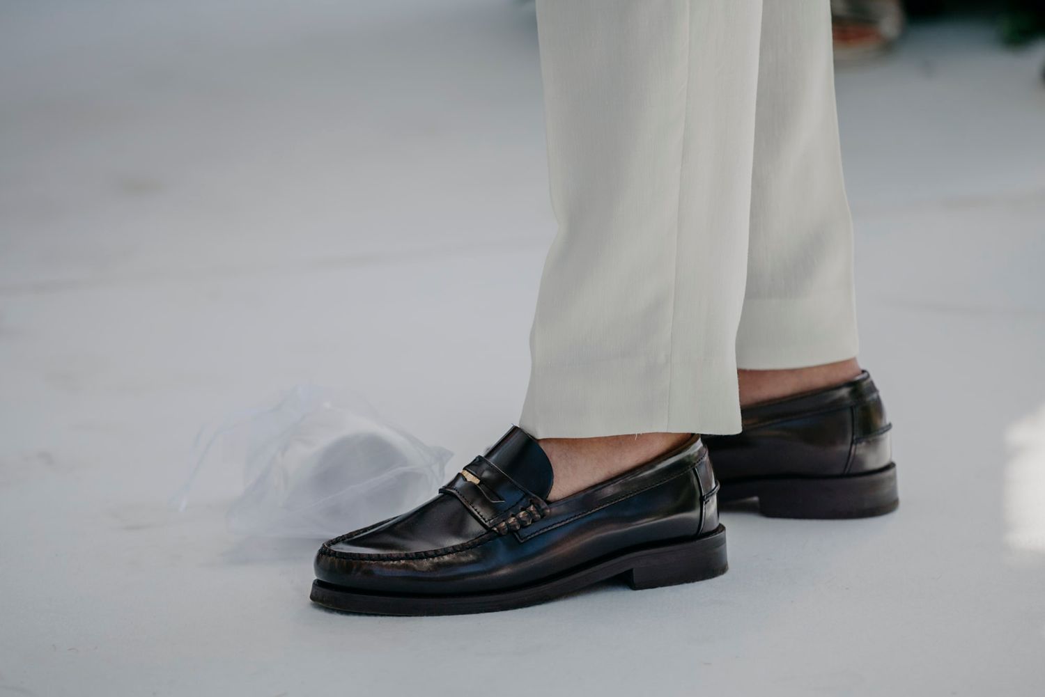 Close-up of formal wedding shoes and attire on a light colored floor.