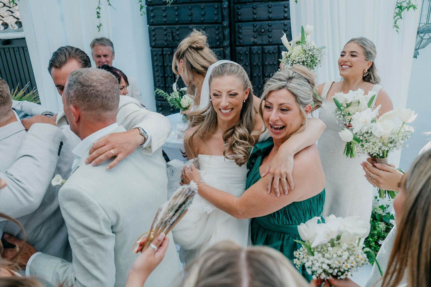 Wedding party celebrates joyfully during reception with white and green decor elements.