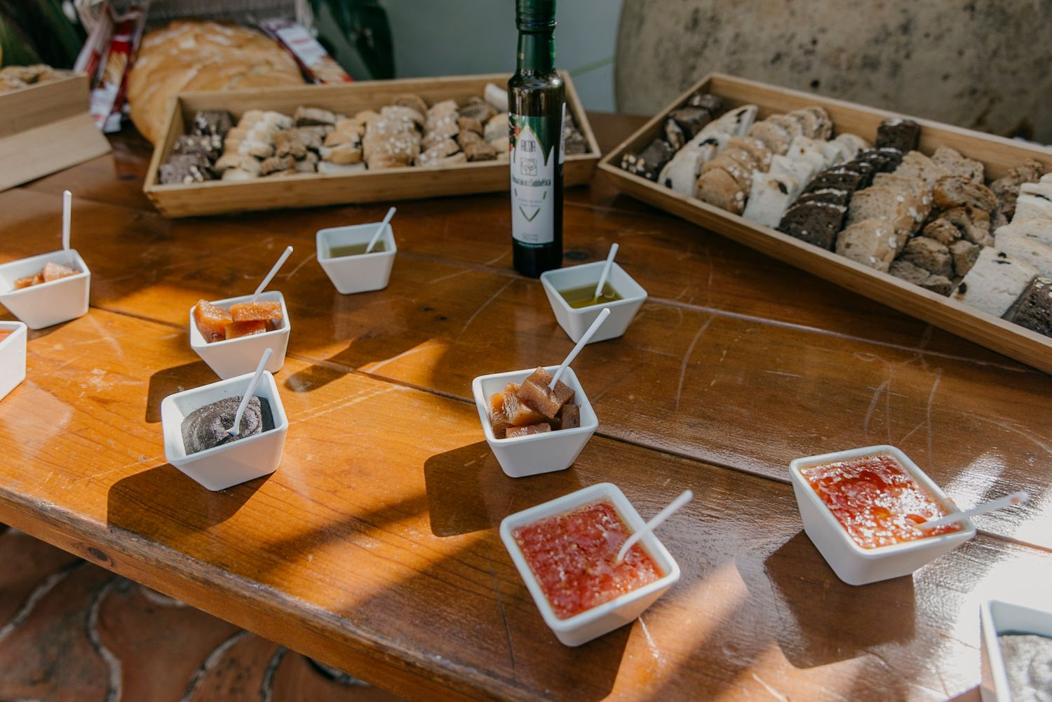 Various sauces and condiments displayed in small white bowls on a wooden table with oysters in serving trays.