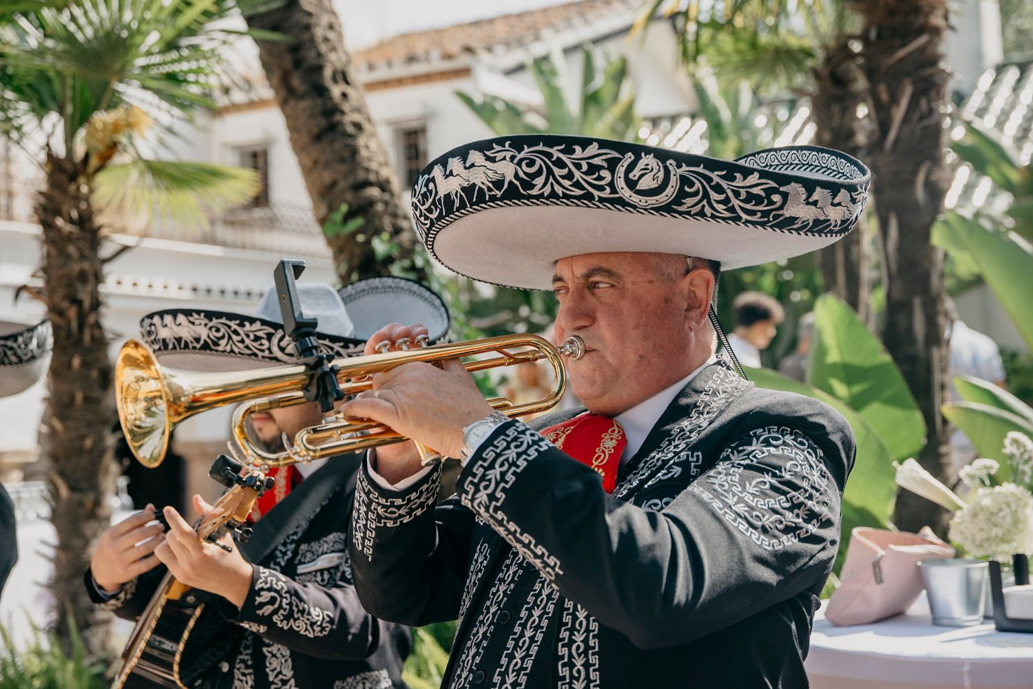 Mariachi band performing in traditional attire with sombreros at an outdoor event.