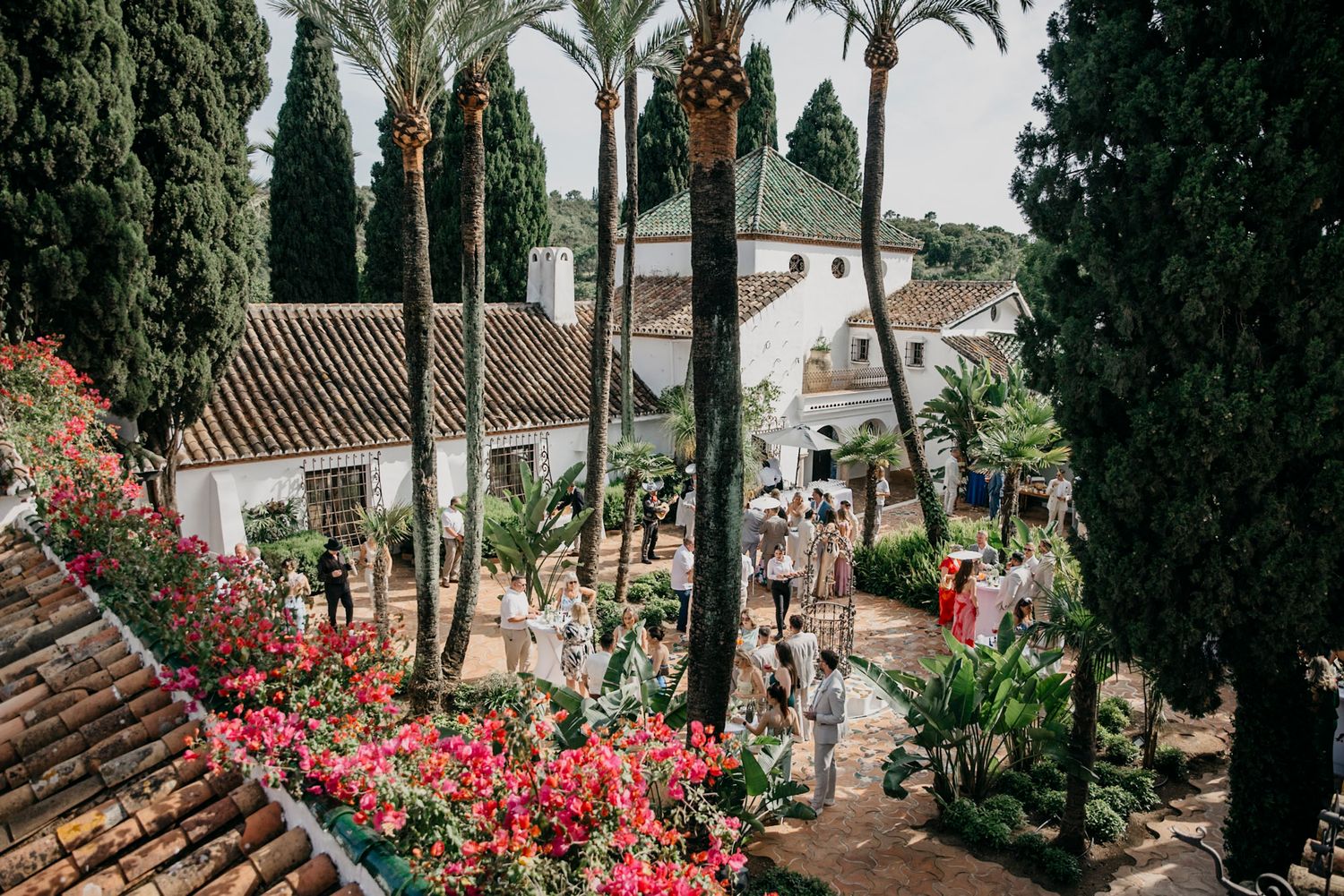 Mediterranean style venue with palm trees and red bougainvillea flowers.