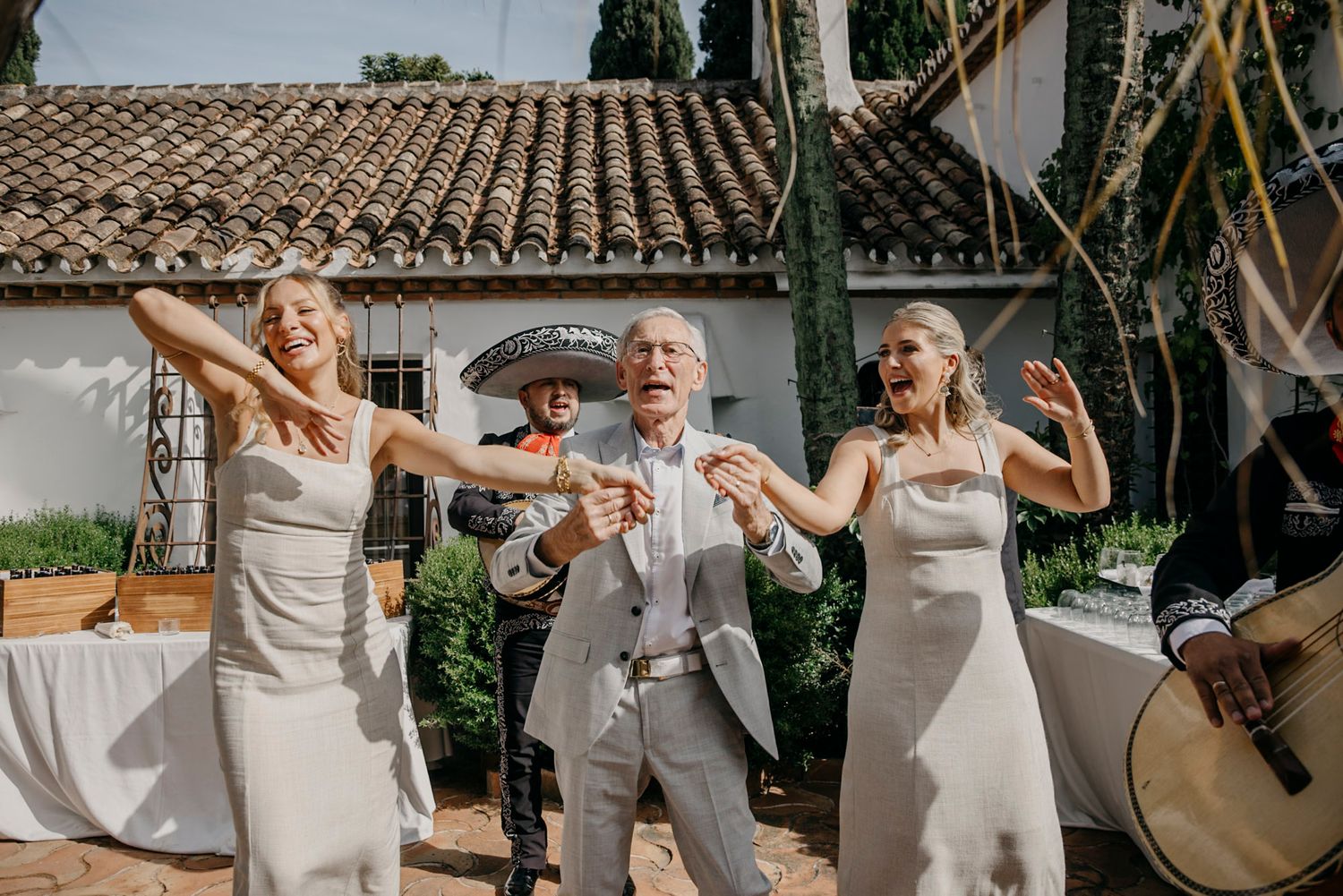 Wedding party celebrating with joyful poses in an outdoor garden setting.