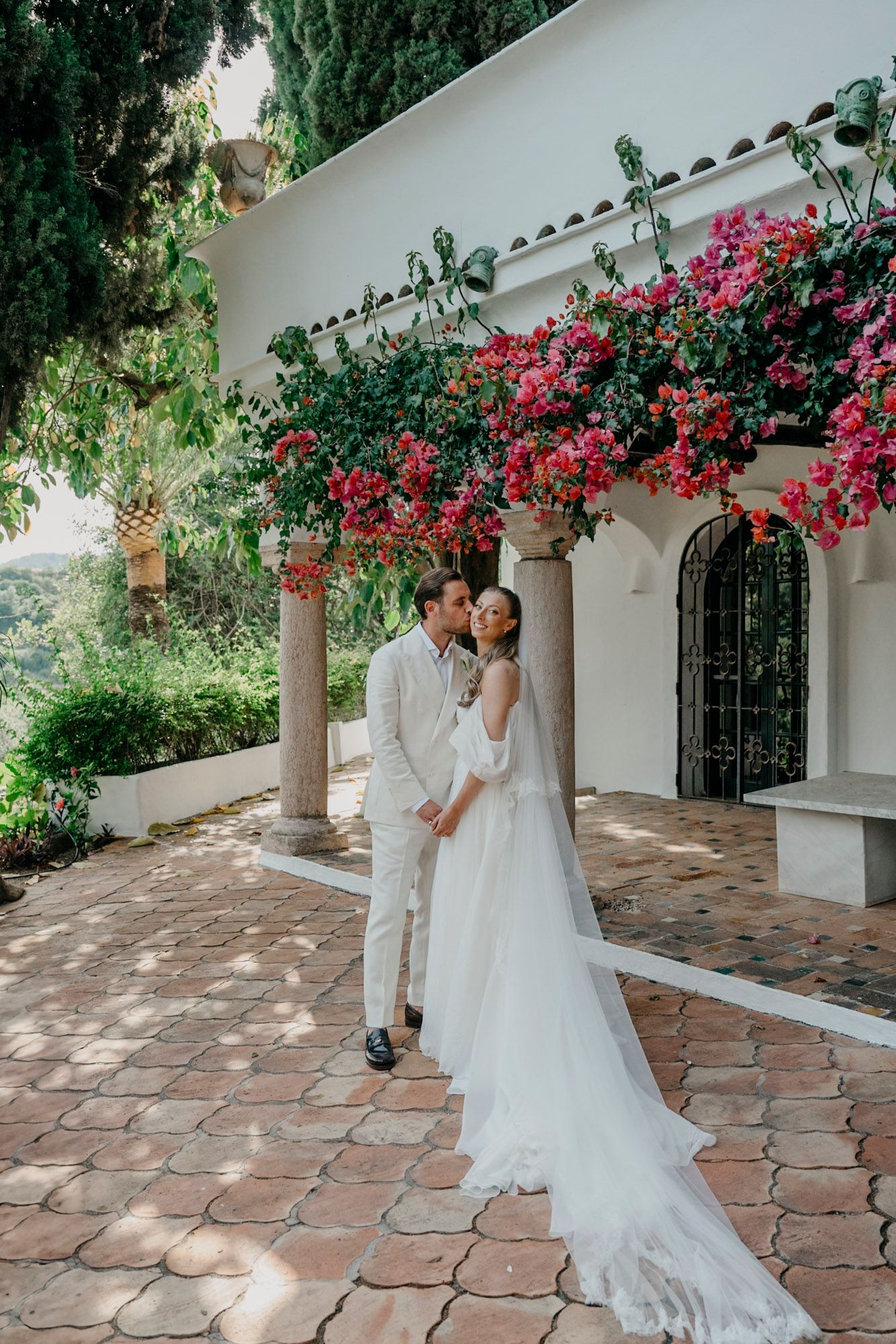 Romantic wedding portraits under blooming bougainvillea on Mediterranean terrace.